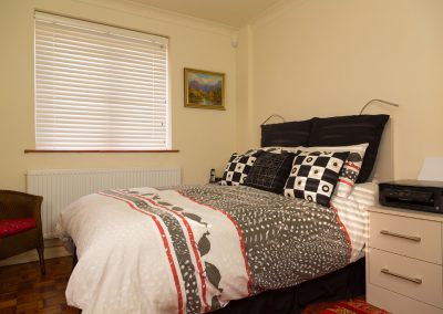 Bedroom with black & white cushions and white venetian blind