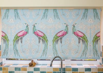 Laminated roller blind with large peacock design at kitchen window