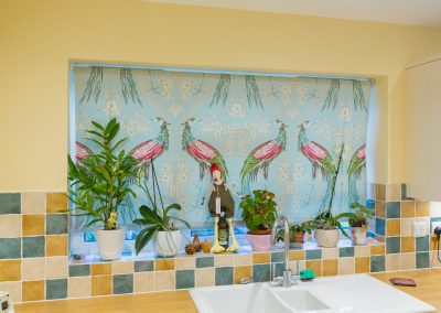 Laminated roller blind with large peacock design at kitchen window