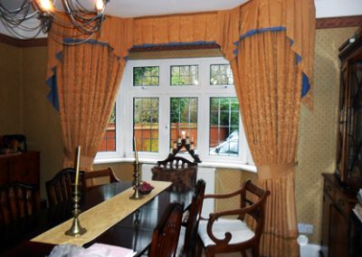 Elaborate floor-length curtains and pelmet at a bay window