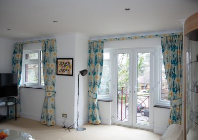 Two pairs of full length curtains with matching tie-backs and small pelmet